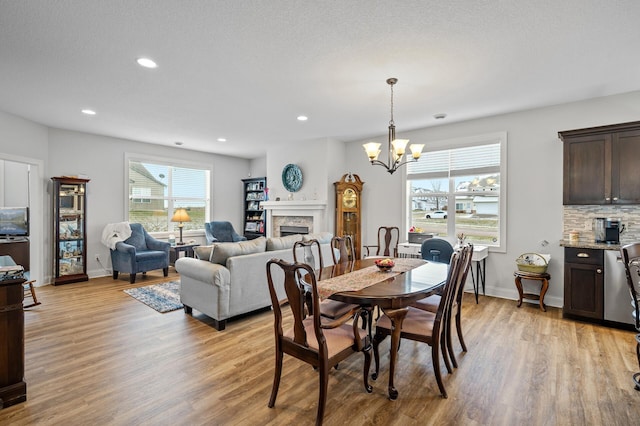 dining area with a chandelier, a textured ceiling, and light hardwood / wood-style floors