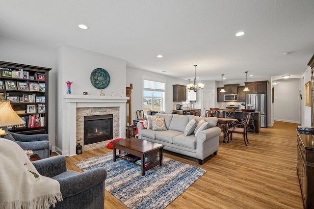 living room featuring a notable chandelier, light hardwood / wood-style floors, and a fireplace