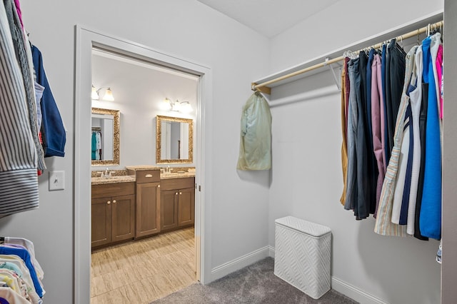 walk in closet with sink and light carpet