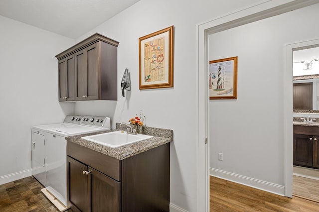 laundry area with cabinets, dark wood-type flooring, washer and dryer, and sink