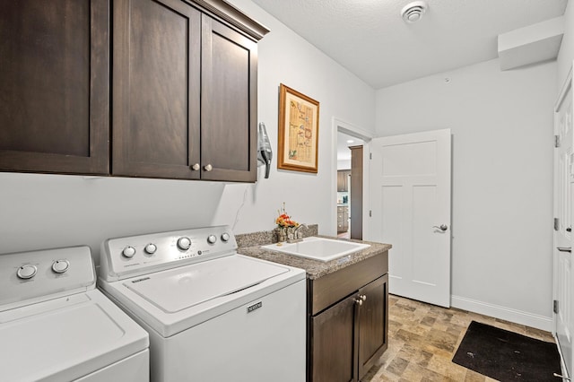 laundry area with a textured ceiling, cabinets, sink, and washing machine and clothes dryer