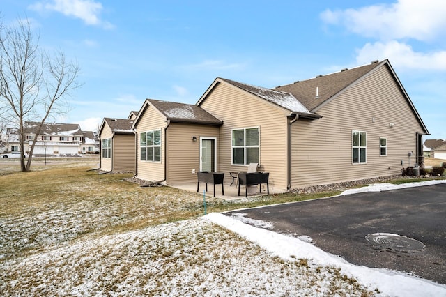 snow covered house featuring central AC unit and a patio