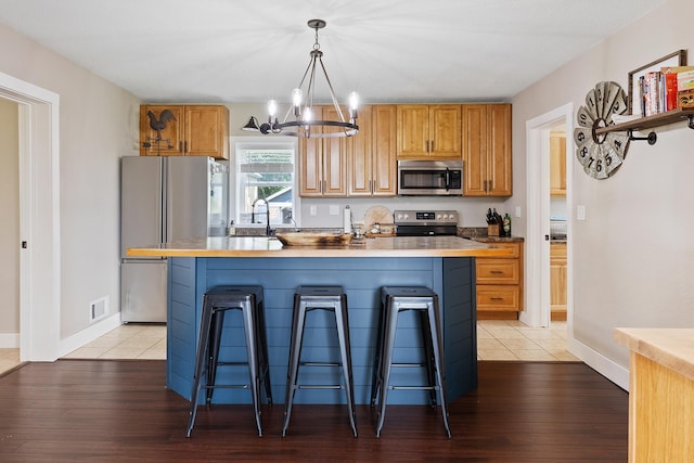 kitchen featuring stainless steel appliances, light hardwood / wood-style flooring, a center island with sink, and a breakfast bar area