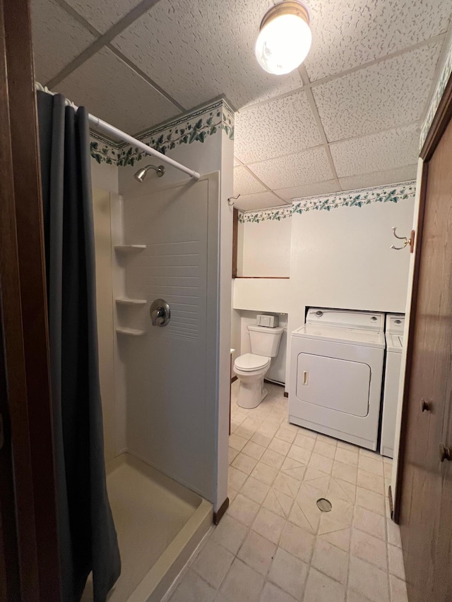 bathroom featuring a shower with curtain, independent washer and dryer, tile patterned floors, toilet, and a paneled ceiling