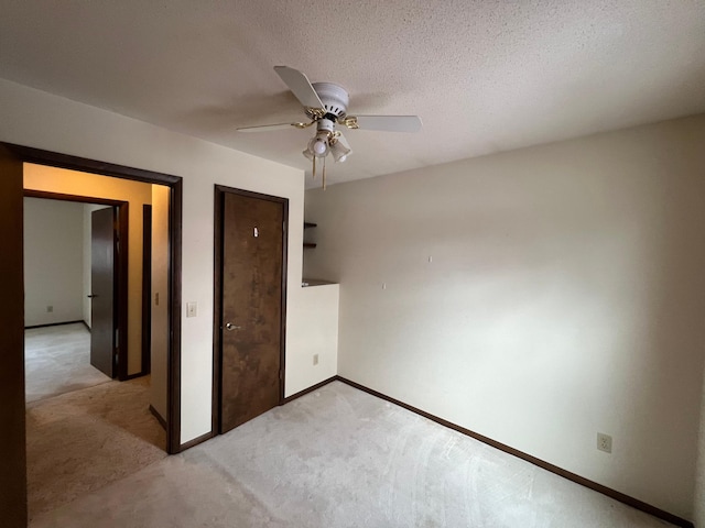 unfurnished bedroom featuring ceiling fan, light colored carpet, and a textured ceiling