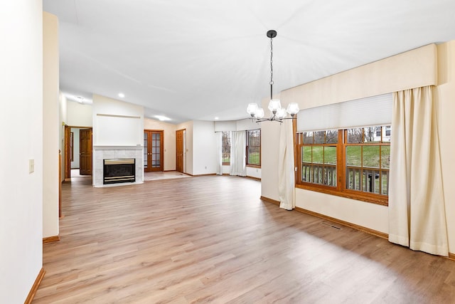 unfurnished living room with a healthy amount of sunlight, light hardwood / wood-style floors, and vaulted ceiling