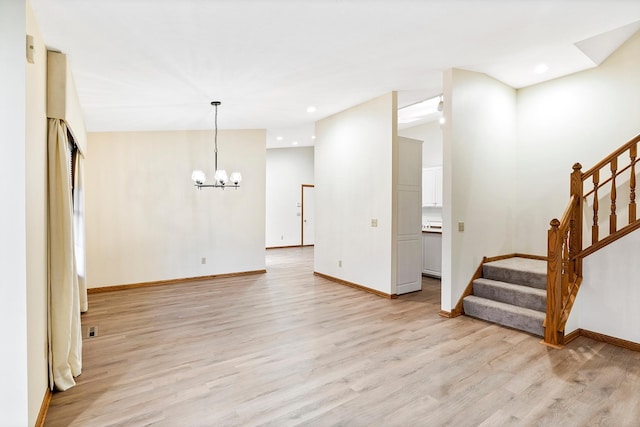 unfurnished living room featuring a notable chandelier and light hardwood / wood-style floors