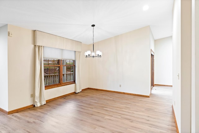 unfurnished dining area featuring light hardwood / wood-style floors and an inviting chandelier