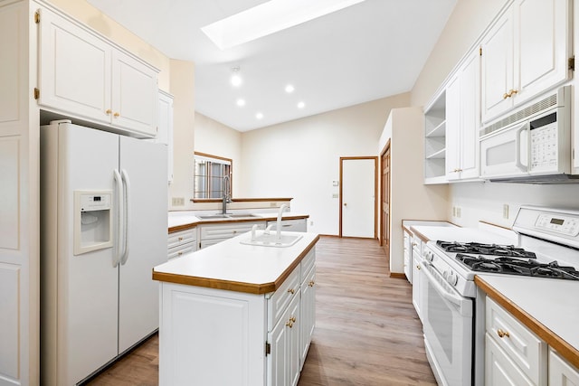 kitchen featuring a kitchen island, white appliances, white cabinetry, and a skylight