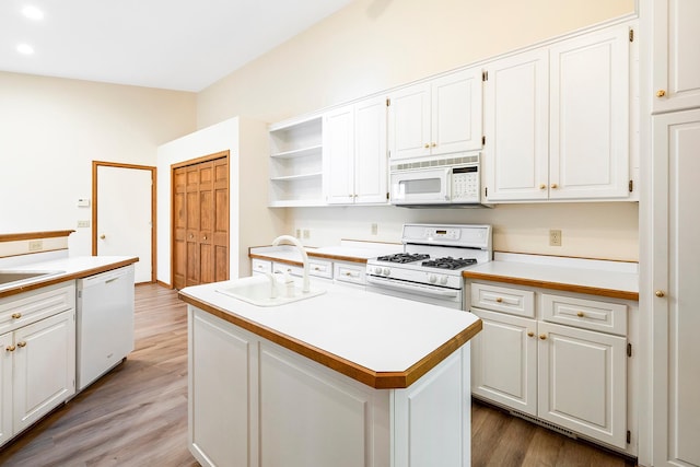 kitchen with white cabinetry, a center island, white appliances, and light wood-type flooring