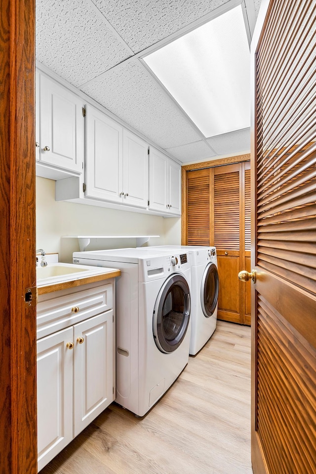 washroom with independent washer and dryer, sink, cabinets, and light wood-type flooring