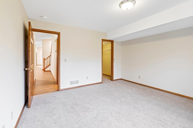 unfurnished bedroom featuring a walk in closet, light carpet, and a closet