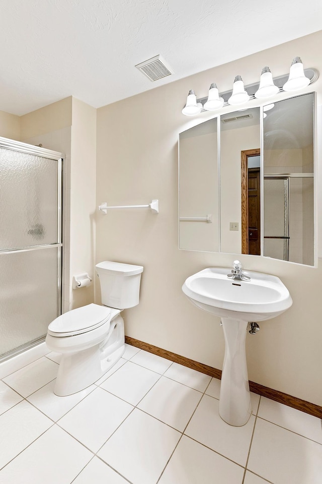 bathroom with tile patterned floors, a shower with shower door, a textured ceiling, and toilet