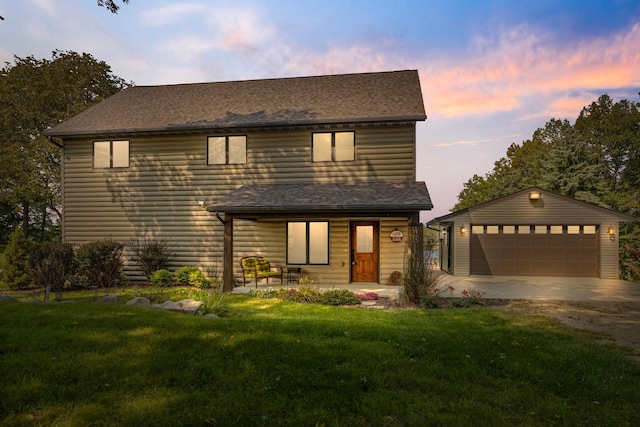 view of front of house featuring roof with shingles, a detached garage, a lawn, and an outdoor structure