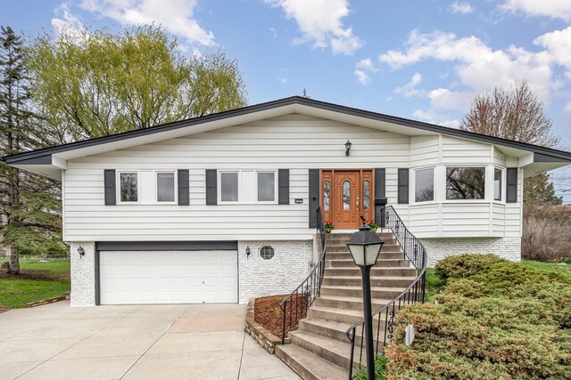 single story home with concrete driveway, a garage, and brick siding