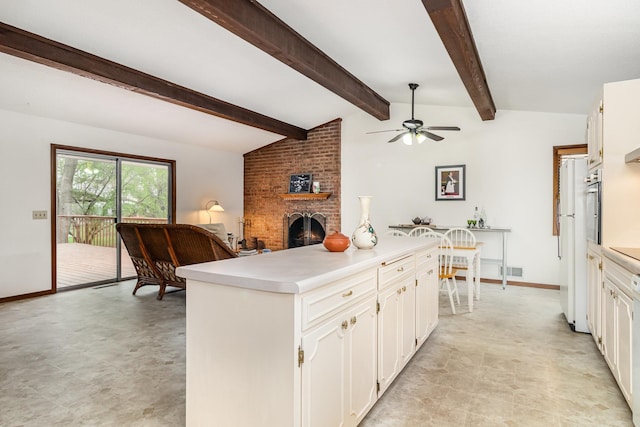 kitchen with a ceiling fan, light countertops, a fireplace, and white cabinetry