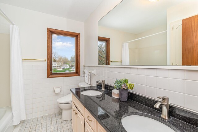 full bathroom with toilet, tile walls, tile patterned floors, and a sink