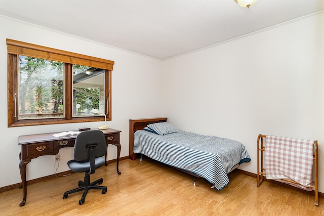 bedroom with light wood finished floors, baseboards, and ornamental molding