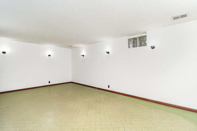 empty room featuring tile patterned floors, visible vents, and baseboards