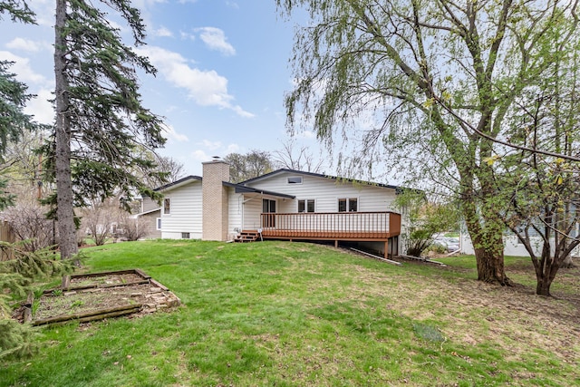 back of property with a lawn, a vegetable garden, a chimney, and a wooden deck