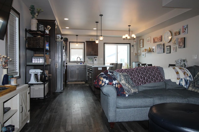 living room with an inviting chandelier, sink, and dark wood-type flooring