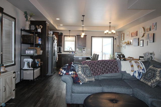 living room with a chandelier, dark hardwood / wood-style flooring, a raised ceiling, and sink