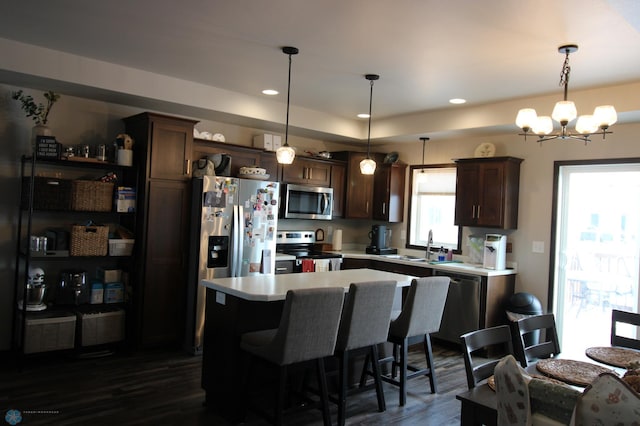 kitchen with dark hardwood / wood-style flooring, appliances with stainless steel finishes, decorative light fixtures, and a center island