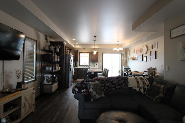 living room with dark wood-type flooring, a chandelier, and sink