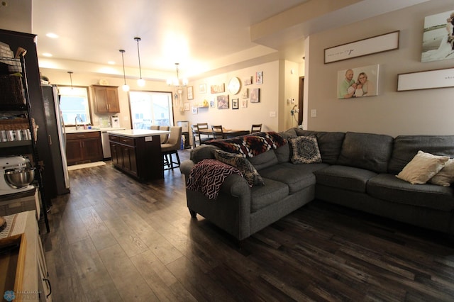 living room with sink, dark hardwood / wood-style floors, and a chandelier