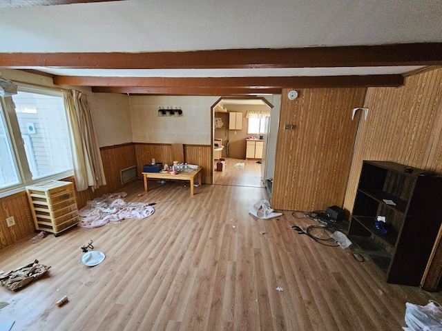 living room with wooden walls, hardwood / wood-style floors, beamed ceiling, and a textured ceiling