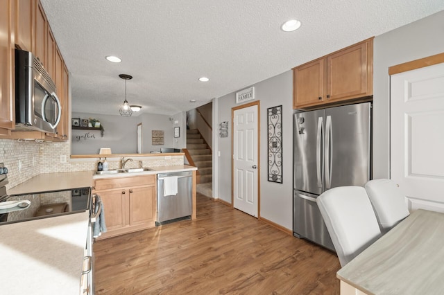 kitchen featuring sink, hanging light fixtures, stainless steel appliances, and a textured ceiling