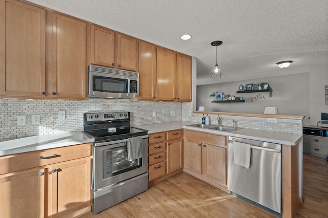 kitchen featuring kitchen peninsula, stainless steel appliances, tasteful backsplash, hanging light fixtures, and sink