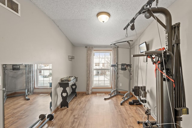 exercise room featuring a textured ceiling, rail lighting, and hardwood / wood-style floors