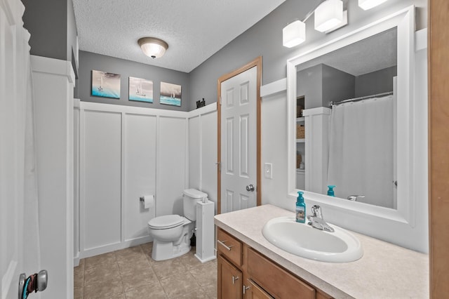 bathroom with a textured ceiling, toilet, and vanity