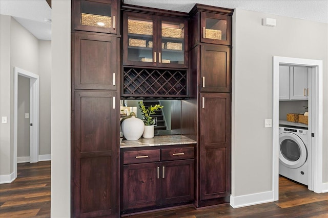 bar with light stone counters, washer / dryer, dark wood-type flooring, and a textured ceiling