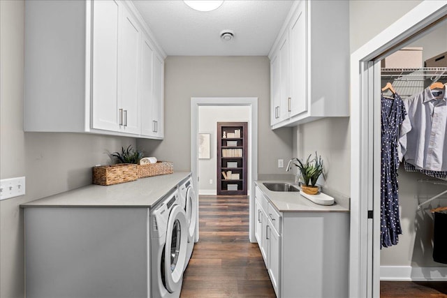 laundry area featuring dark hardwood / wood-style floors, sink, cabinets, washing machine and dryer, and a textured ceiling