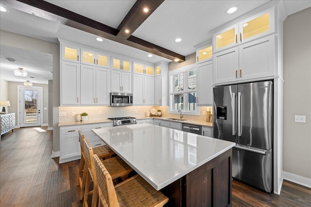 kitchen featuring white cabinets, a center island, beamed ceiling, and appliances with stainless steel finishes