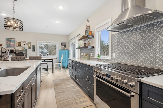 kitchen with pendant lighting, wall chimney range hood, sink, plenty of natural light, and stainless steel appliances