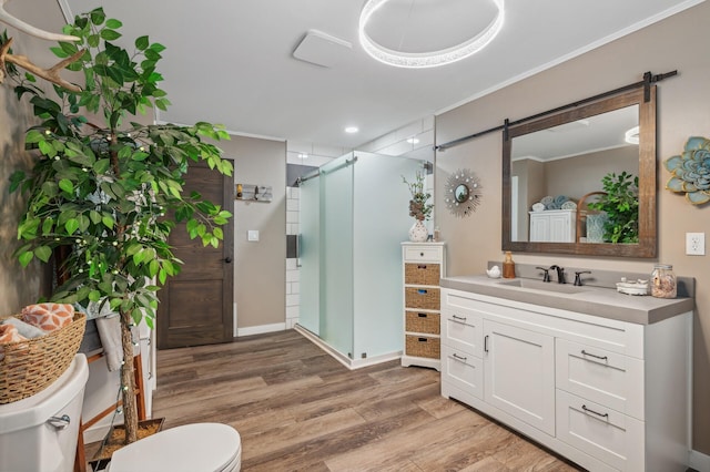 bathroom featuring hardwood / wood-style floors, ornamental molding, vanity, walk in shower, and toilet