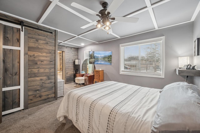 carpeted bedroom with coffered ceiling, ceiling fan, wooden walls, and a barn door