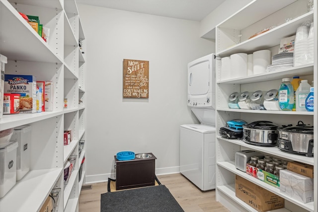 washroom featuring light hardwood / wood-style floors and stacked washer / dryer