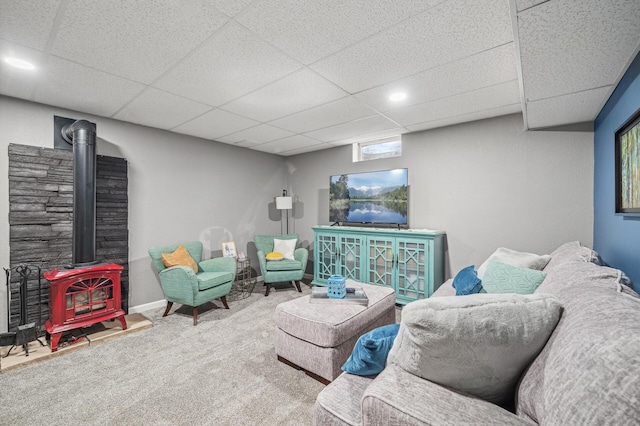 carpeted living room with a drop ceiling and a wood stove