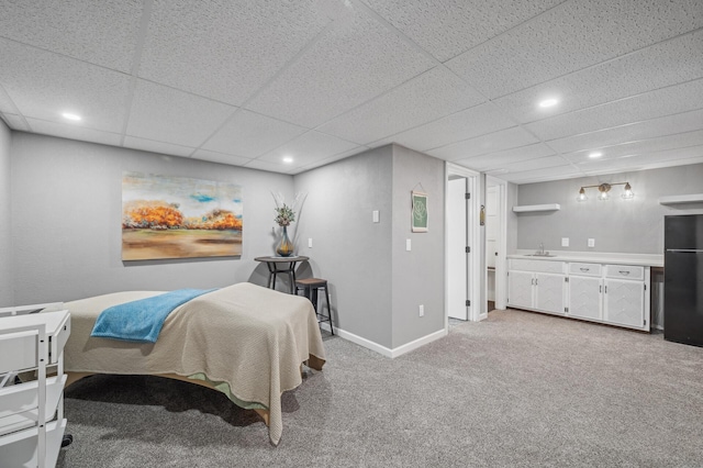 carpeted bedroom with a paneled ceiling, black refrigerator, and sink