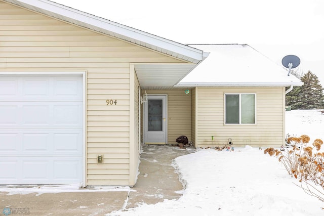 snow covered property entrance with a garage