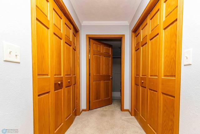 hallway featuring a textured ceiling, light colored carpet, and crown molding