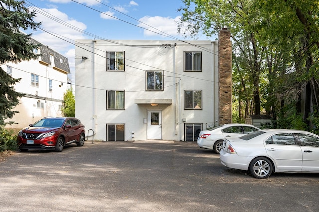 5136 Hiawatha Ave Unit 002, Minneapolis, MN 55417 - view of front of property featuring stucco siding, a chimney, and uncovered parking