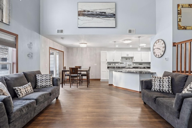 living room featuring a towering ceiling, dark hardwood / wood-style floors, and a healthy amount of sunlight