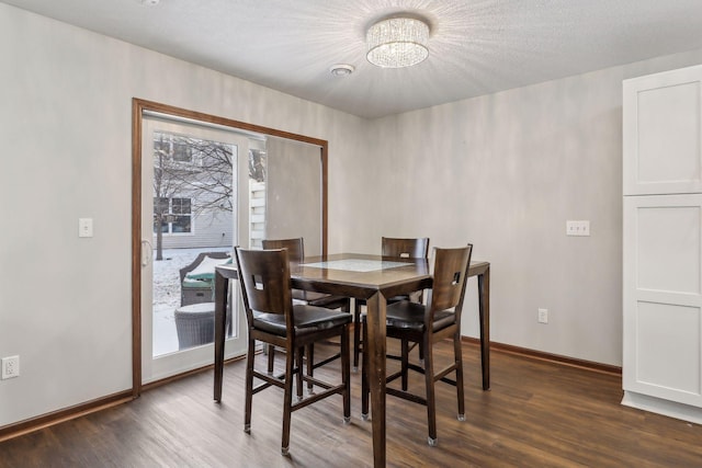 dining area with a textured ceiling, dark hardwood / wood-style flooring, and a notable chandelier