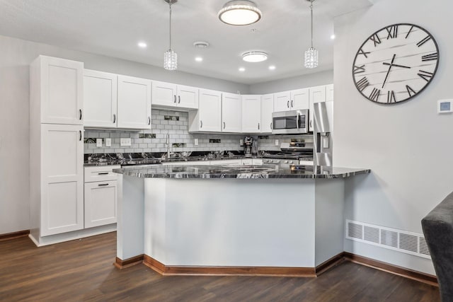 kitchen featuring white cabinets, decorative light fixtures, dark hardwood / wood-style flooring, and stainless steel appliances