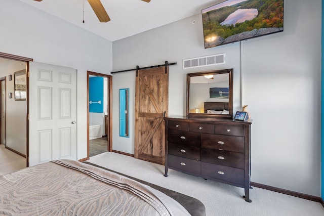 carpeted bedroom featuring ceiling fan, a barn door, and ensuite bath